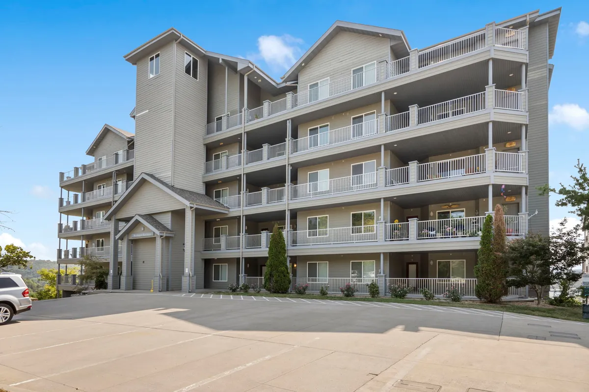 A welcoming exterior perspective of the condo building, showcasing its modern architecture, landscaped grounds, and private balconies. The building’s design reflects accessibility and comfort, ideal for guests of all ages.