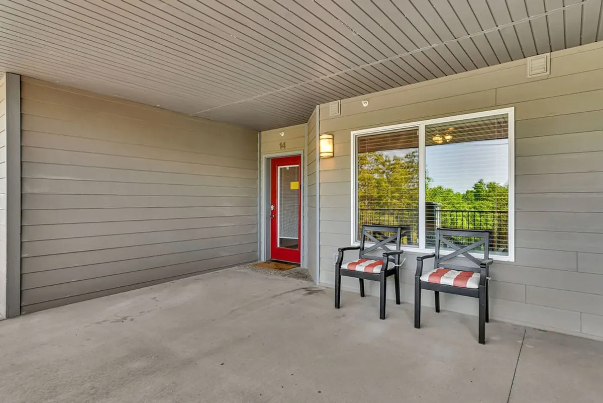 An inviting exterior with a bright red door, two comfortable chairs, and a window with scenic views. The space feels welcoming and offers a quiet spot for morning coffee, reading, or enjoying the peaceful surroundings.