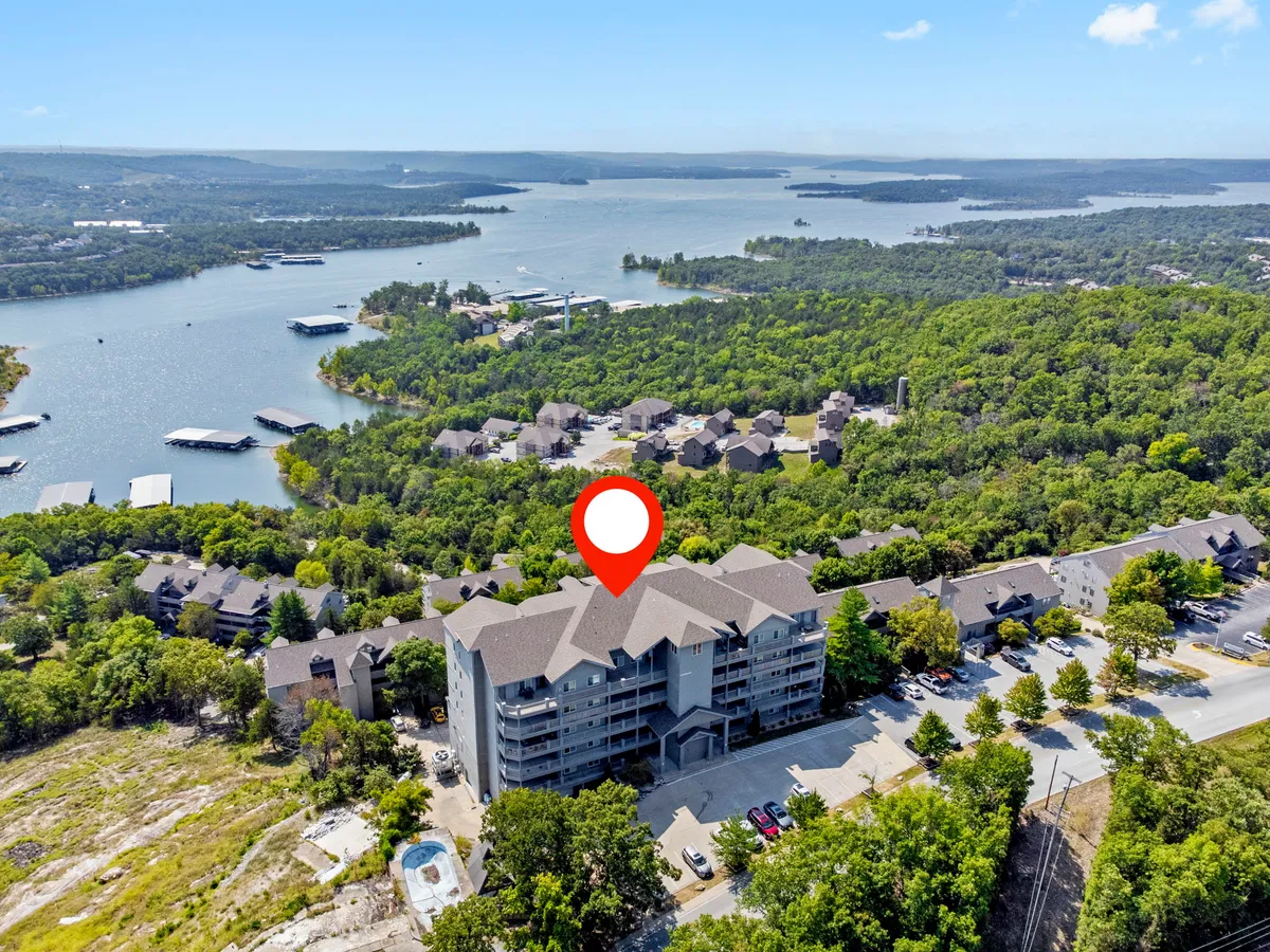 A serene exterior shot featuring the condo building overlooking the tranquil lake, surrounded by lush greenery. The image also hints at proximity to walking trails and offers a glimpse of the single-level living spaces with elevator access.