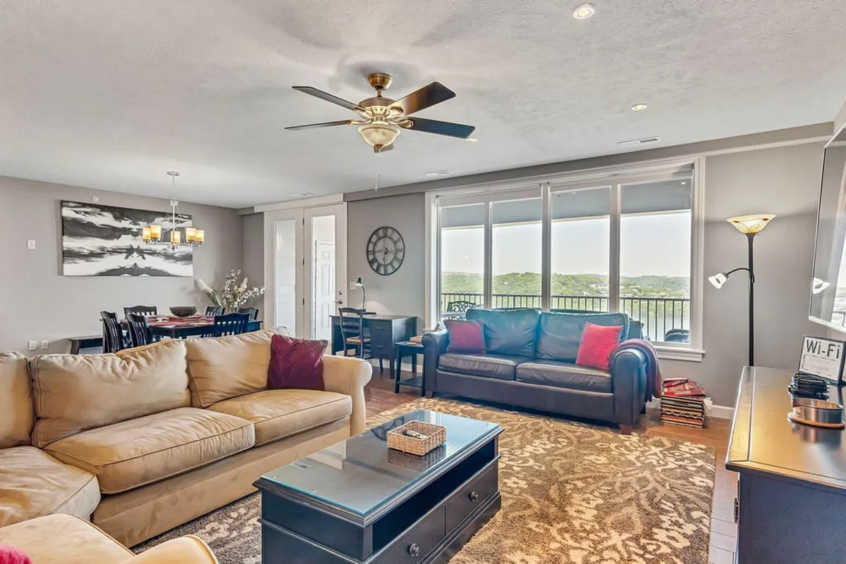 A cozy interior living space featuring comfortable couches, a dining table, and large windows offering scenic views. The room is decorated with inviting wall art and gets plenty of natural light, setting a welcoming atmosphere for group gatherings or quiet relaxation.