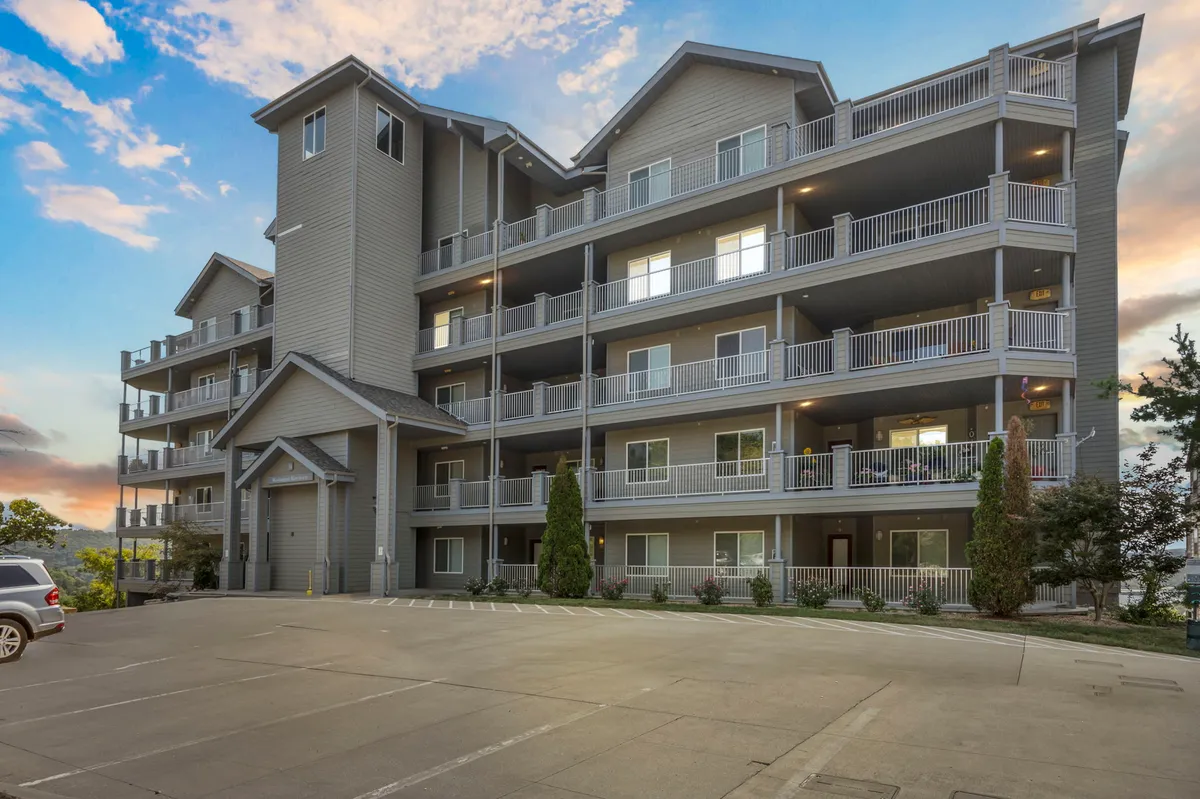 This exterior shot features the multi-story building of Hawthorne 1414 with balconies that overlook beautifully landscaped grounds. The image conveys a sense of community and leisure, with the potential for residents to enjoy quiet mornings or sunset views from their private balconies.