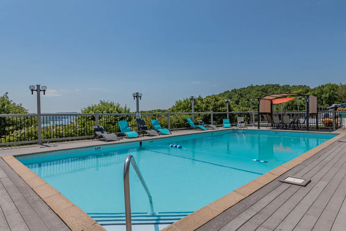 A refreshing swimming pool with ample lounge chairs and shaded canopy seating area, set in a welcoming exterior environment. The resort vibe invites socializing, sunbathing, and easy enjoyment of communal outdoor features.